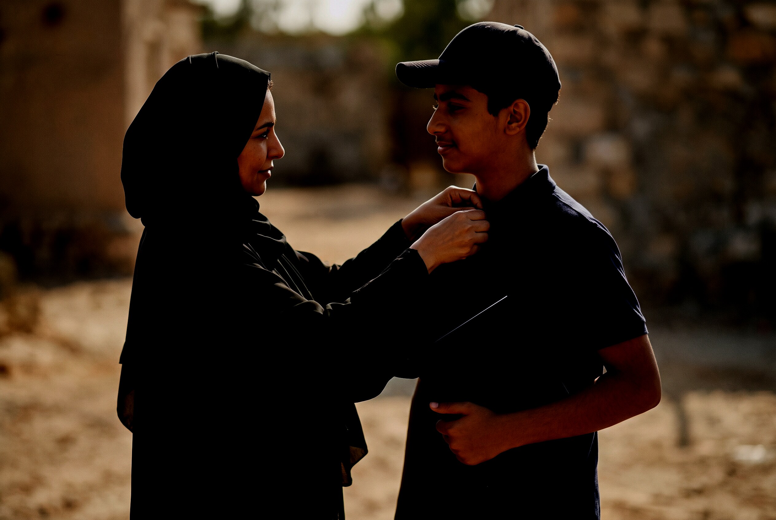 An Emirati mother adjusting her son's collar at an evening ceremony, his Aviation Passport in hand